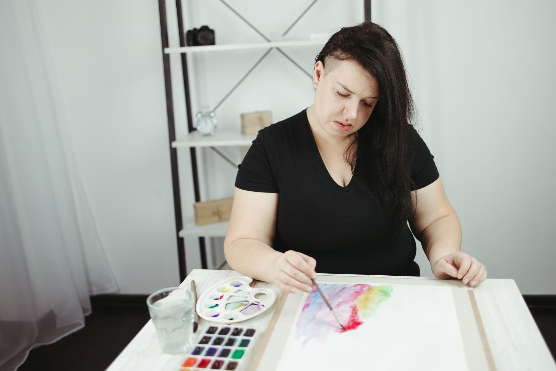 Young concentrated woman do watercolor drawing